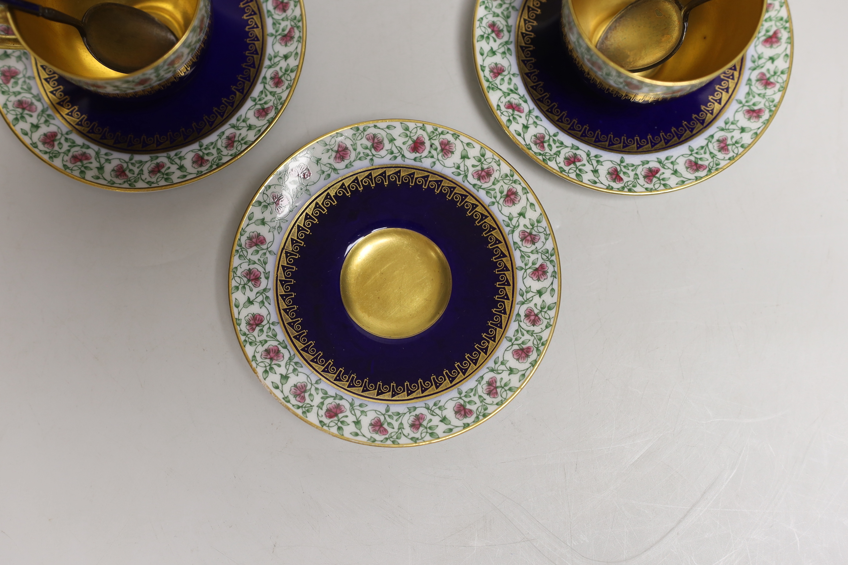 A set of six Royal Worcester porcelain coffee cups and saucers, together with a set of six silver and blue enamelled spoons